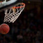 Basketball beneath a hoop on an indoor court; generic basketball image, not an NBA game photo.