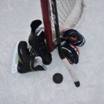 Hockey skates, puck, gloves and stick illustrating beginner hockey equipment