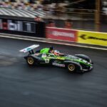 Generic open-wheel race car on a wet track, used as motorsports illustration; not the Daytona 500 or Indianapolis 500