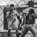 Two mixed martial arts athletes sparring inside a fenced training cage