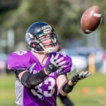 American football player reaching to catch a pass