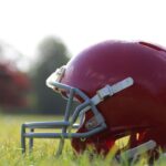 American football helmet on the field with a player blurred in the background
