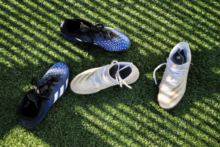 Sports shoes and cleats on grass illustrating surface and traction choices